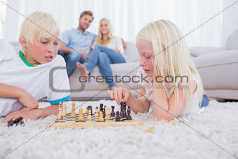 Parents looking at their children playing chess