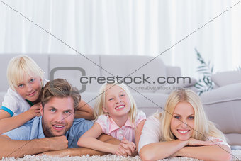 Smiling family lying on the carpet