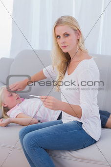 Concerned mother checking her daughters temperature