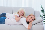 Mother lying on couch with her daughter on her back