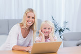 Smiling mother using laptop with her daughter