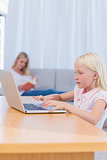 Little girl typing on laptop in the living room
