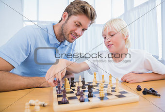 Boy playing chess with his father