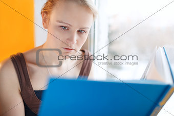 Young woman reading a book with blue cover