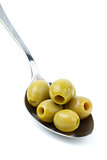 Five marinated pitted green olives in the metal spoon