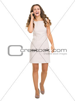 Full length portrait of smiling young woman talking mobile phone
