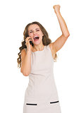 Happy young woman talking cell phone and rejoicing