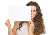 Portrait of happy young woman hiding behind blank paper