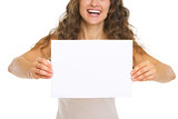 Closeup on smiling young woman showing blank paper