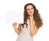 Thoughtful young woman holding blank paper