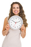 Smiling young woman showing clock