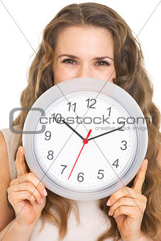 Young woman hiding behind clock