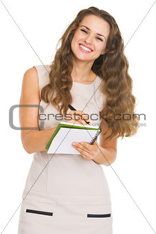 Smiling young woman writing in notepad