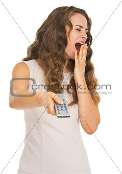 Yawing young woman switching channels with tv remote control