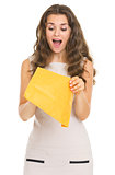 Surprised young woman opening letter