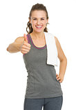 Smiling fitness young woman showing thumbs up