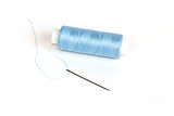Blue bobbin of thread with needle on white
