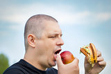 Man with burger and apple in the hands