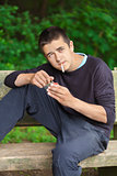 Boy with a cigarette on a bench in the park