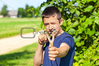 Boy with a slingshot at outdoors in summer