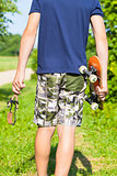 Boy with a slingshot and skateboard on rural road