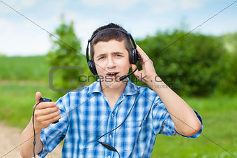 Boy with headphones and Mic on rural road in summer