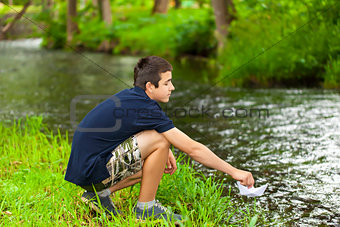 Boy with paper boat near the river