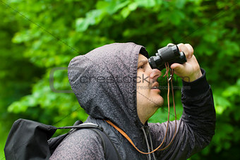 Man with binoculars watching birds in the park