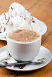 Cappuccino with foam and meringues on white plate