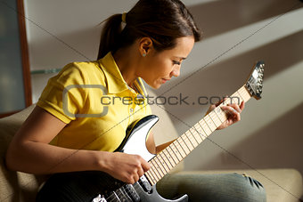woman playing and training with electric guitar at home