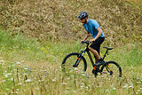 Mountain Biker Riding His Bike Through the Meadow