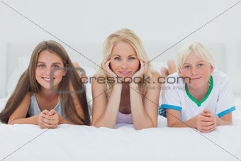 Siblings and mother lying on bed
