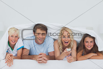 Cheerful family hiding under the blanket