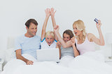 Family using a laptop in bed
