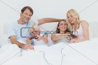 Family playing video games in bed