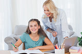 Smiling mother and daughter doing homework
