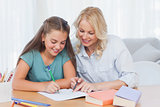 Smiling mother helping daughter with homework