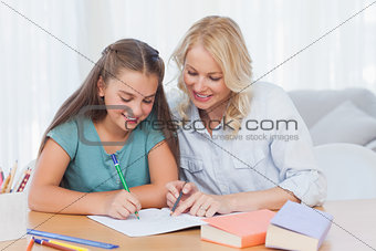 Smiling mother helping daughter with homework