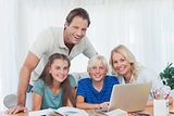 Smiling family using the laptop together to do homework