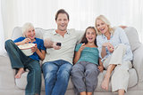Family watching television sitting on sofa