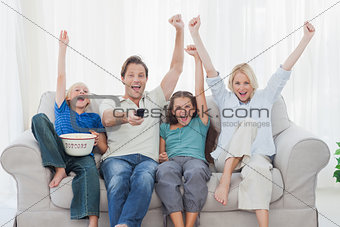 Family watching television and raising arms