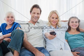 Parents posing with children and watching television