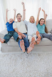 Portrait of a family watching television and raising arms