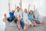 Family sitting on a couch and raising arms