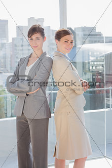 Businesswomen standing back to back and smiling