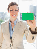 Smiling businesswoman holding up green business card