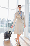 Businesswoman pulling her suitcase and smiling at camera