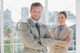 Smiling business partners with arms crossed