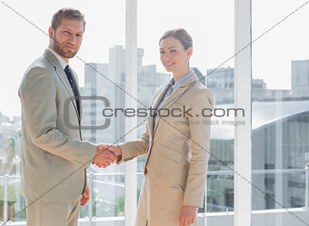Business people shaking hands and smiling at camera