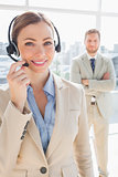 Smiling call centre agent with colleague behind her